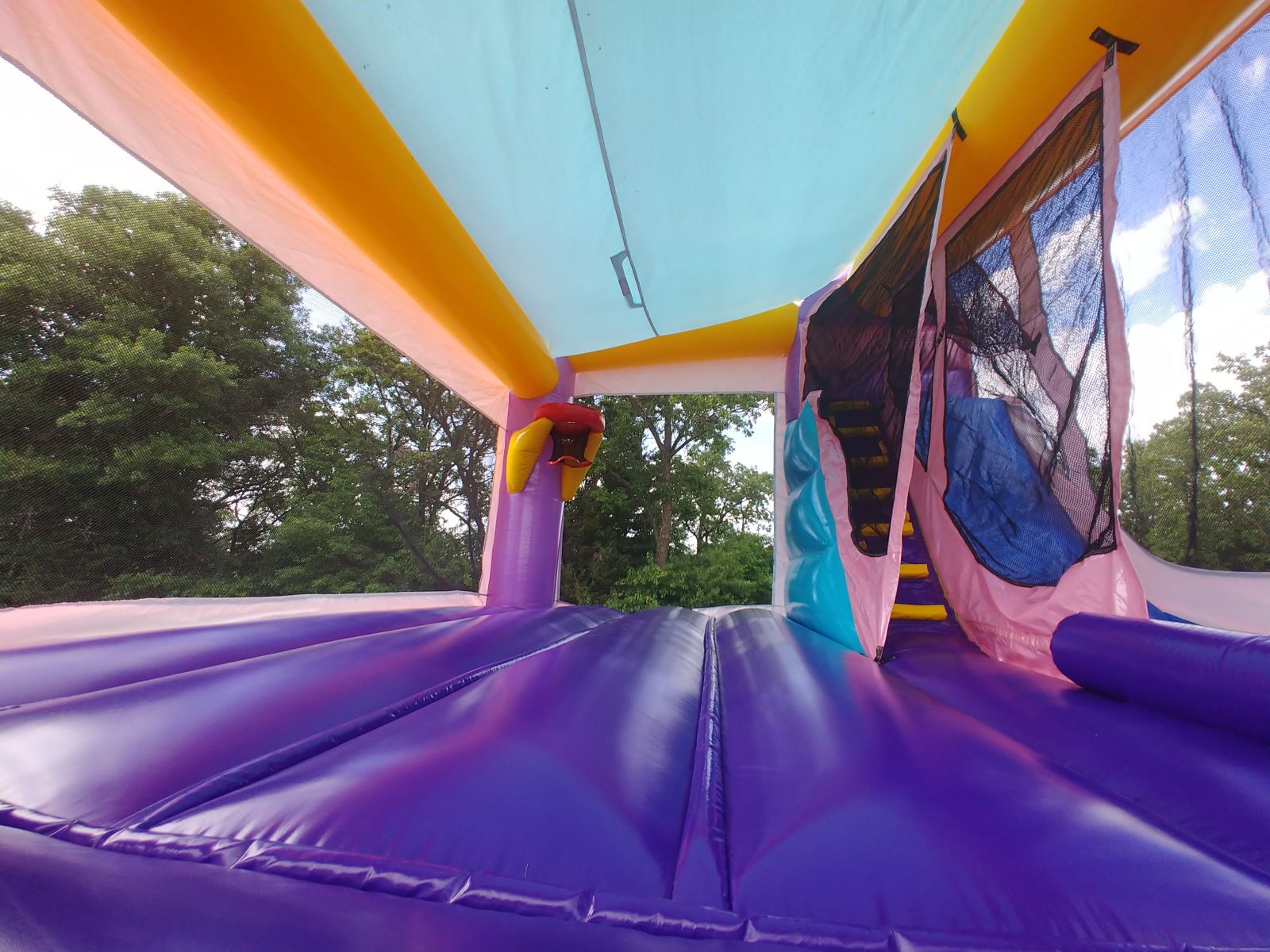 Entrance view of inflatable combo jumping area with basketball hoop and slide